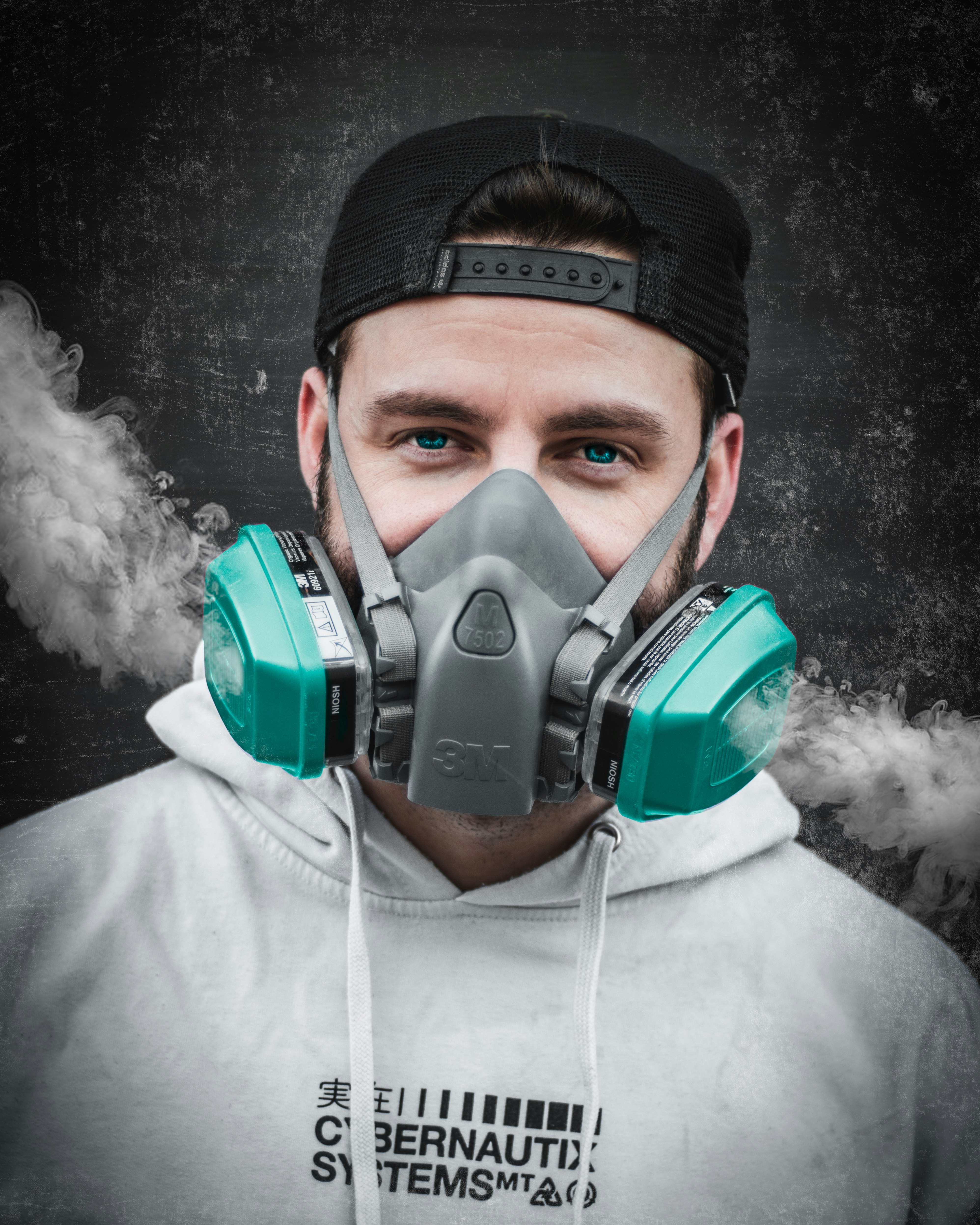 man in white hoodie wearing green gas mask